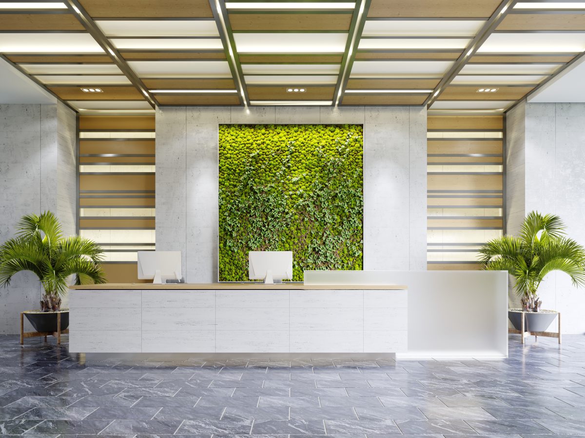 White reception desk in an office building with a green wall and illuminated wood paneling and flowerpots. 3D rendering.